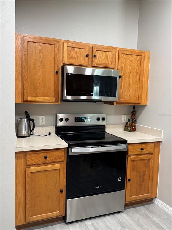 A kitchen features oak cabinets, a stainless steel microwave, and a black electric range — 1126 SANDY RIDGE DRIVE, DAVENPORT, FL