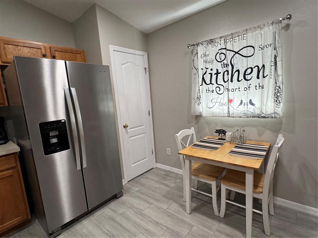 A kitchen breakfast nook features a stainless steel refrigerator, a small wooden table, and chairs — 1126 SANDY RIDGE DRIVE, DAVENPORT, FL