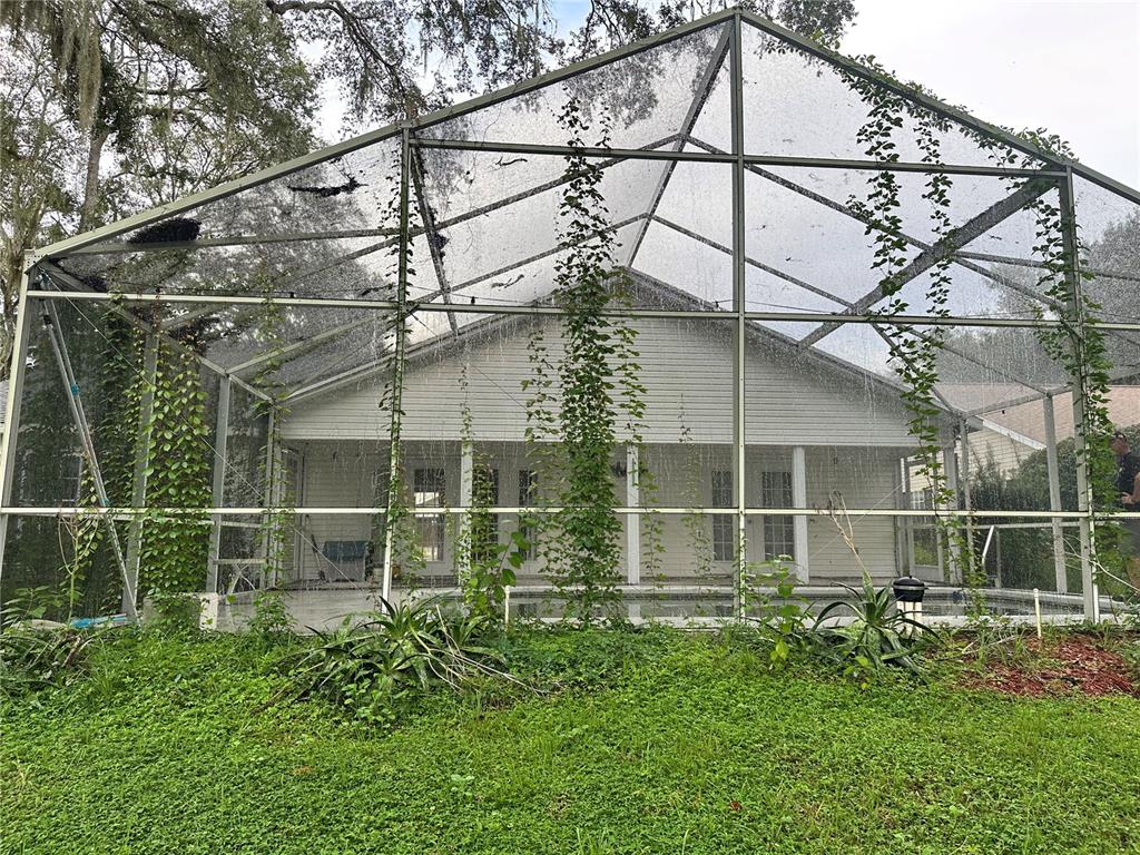 A backyard view of a house with a pool enclosed by a large screened lanai — 4242 LEAFWAY CIRCLE, LEESBURG, FL