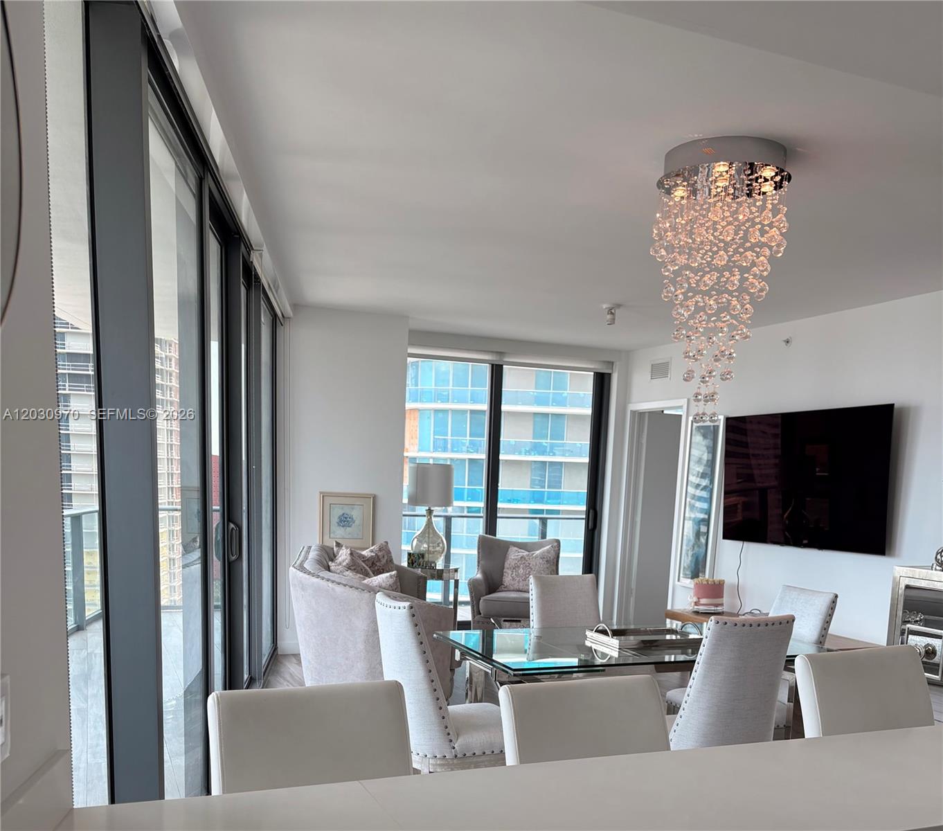 A modern dining area features a glass table, upholstered chairs, and a crystal chandelier — 1300 S Miami Ave # 2205, Miami FL 33130, MIAMI, FL