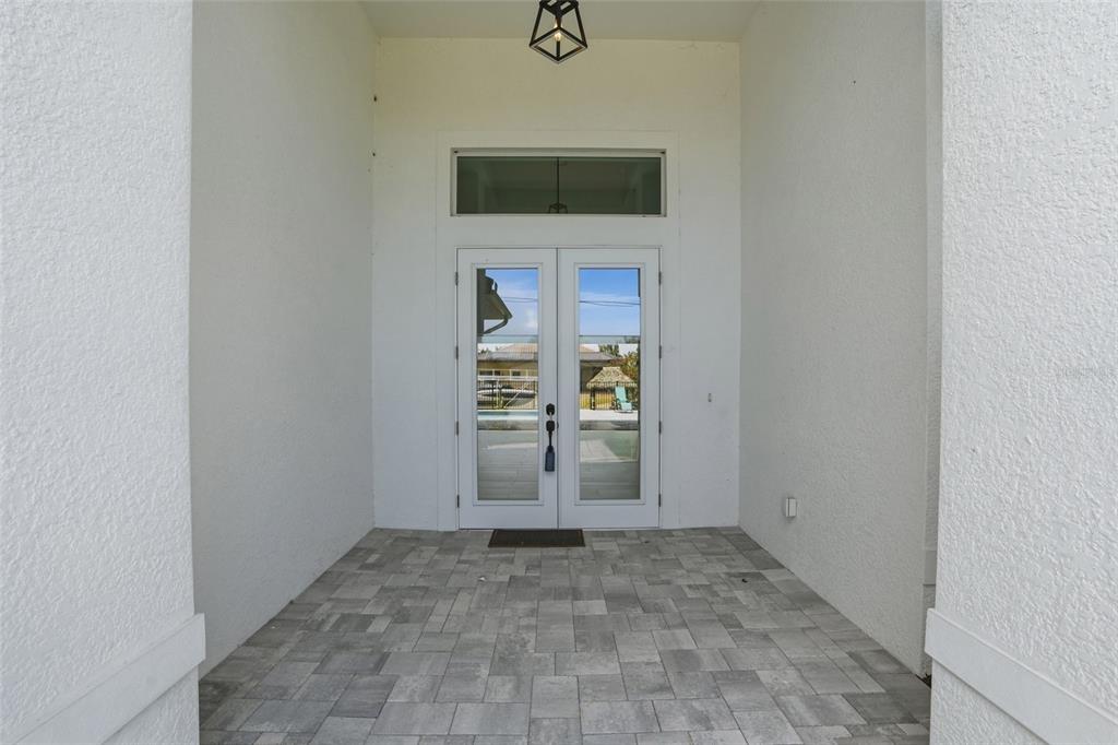 A covered entryway features white walls, a tiled floor, and double glass doors — 1625 SW 44TH TERRACE, CAPE CORAL, FL