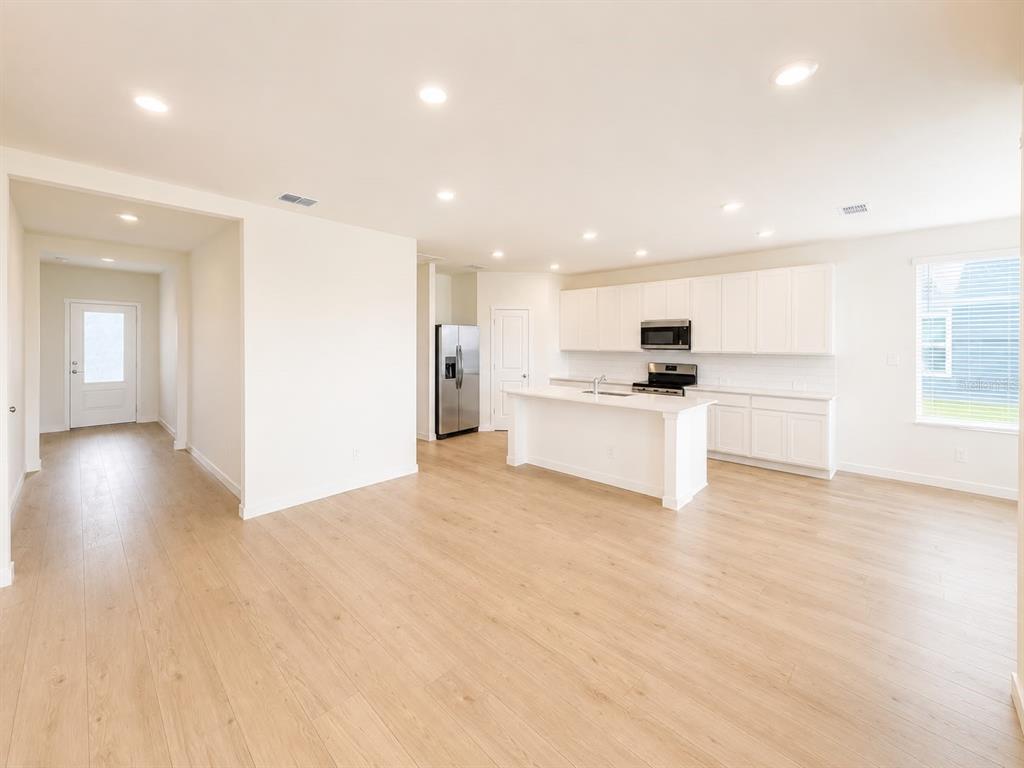 An open-concept kitchen and living area features white cabinetry, a central island, and light-colored flooring — 644 RUTH AVENUE, HAINES CITY, FL