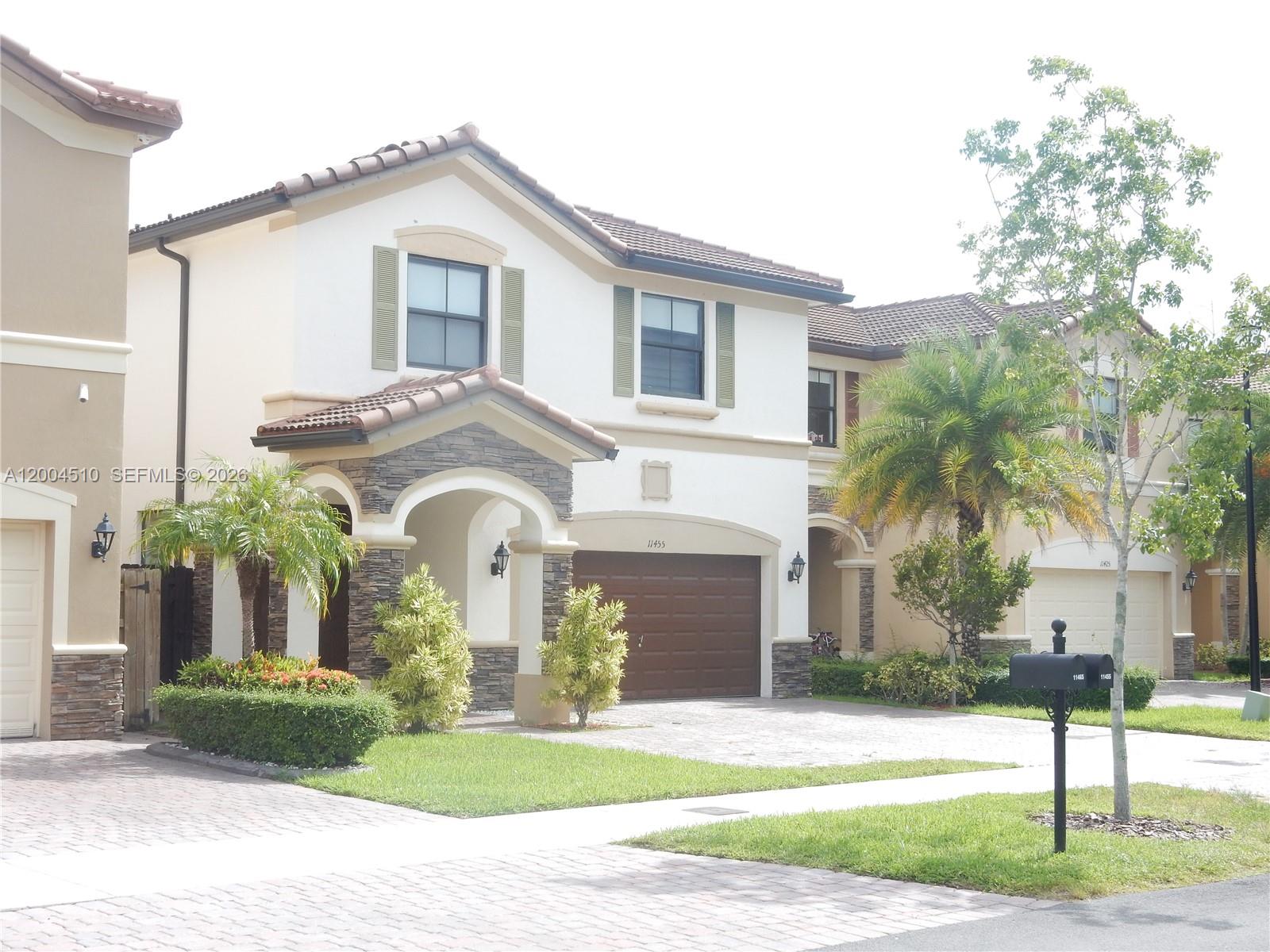 A two-story suburban house with a brown garage door and stone-accented entryway — 11455 NW 88th Ln, Doral FL 33178, DORAL, FL