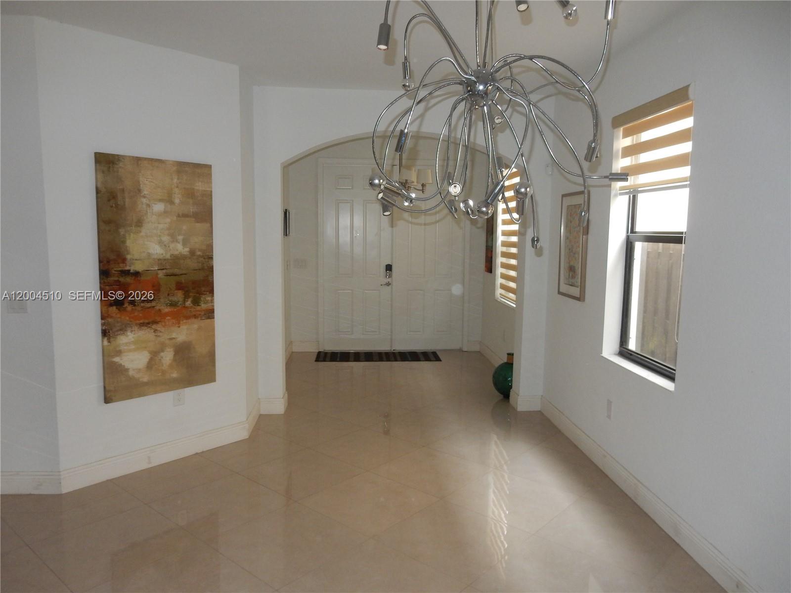 A bright entryway features tile flooring, a large modern chandelier, and a double front door — 11455 NW 88th Ln, Doral FL 33178, DORAL, FL