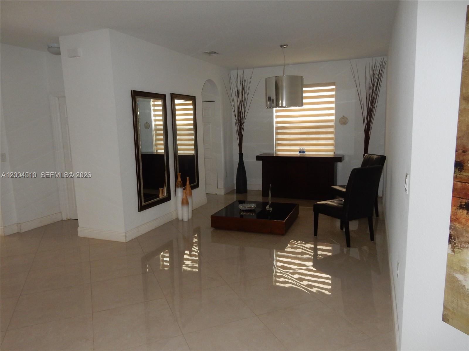 A living room features tile floors, two mirrors, a coffee table, and two black chairs — 11455 NW 88th Ln, Doral FL 33178, DORAL, FL