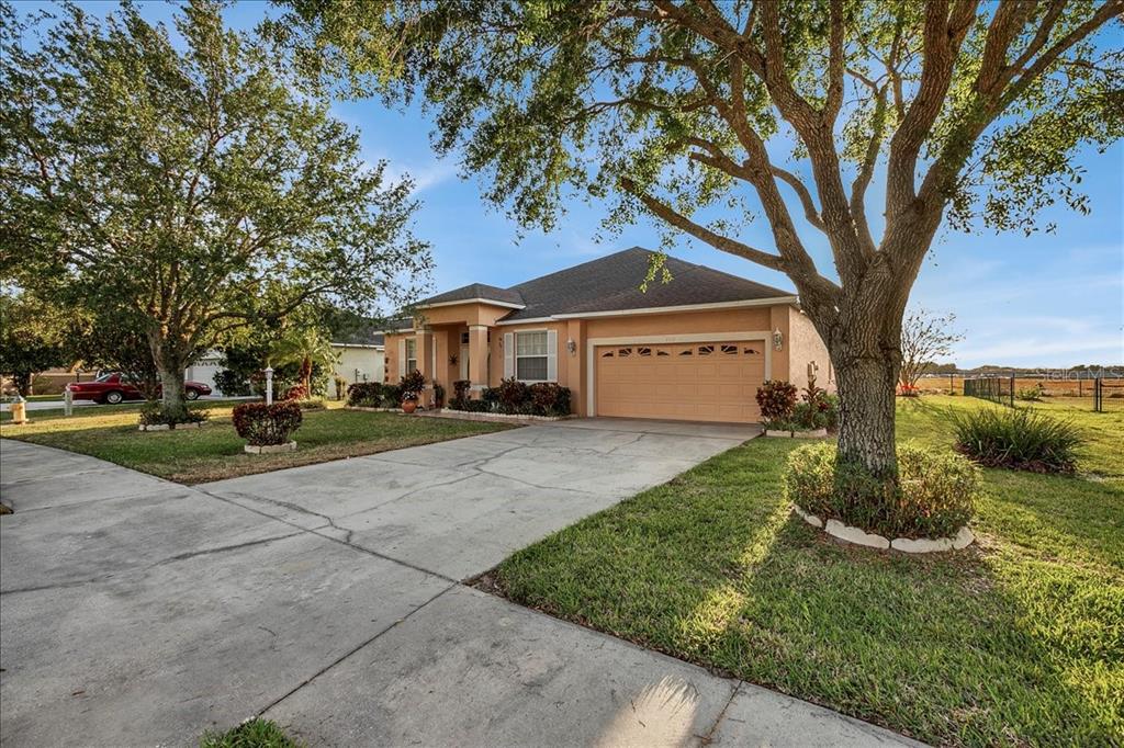 A single-story peach-colored house with a two-car garage and a concrete driveway — 4319 DINNER LAKE BOULEVARD, LAKE WALES, FL