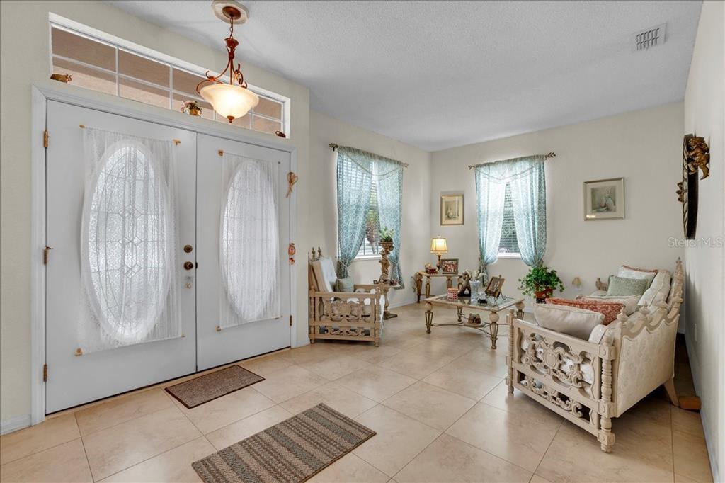 A bright entryway features tile flooring, double front doors, and a formal seating area — 4319 DINNER LAKE BOULEVARD, LAKE WALES, FL
