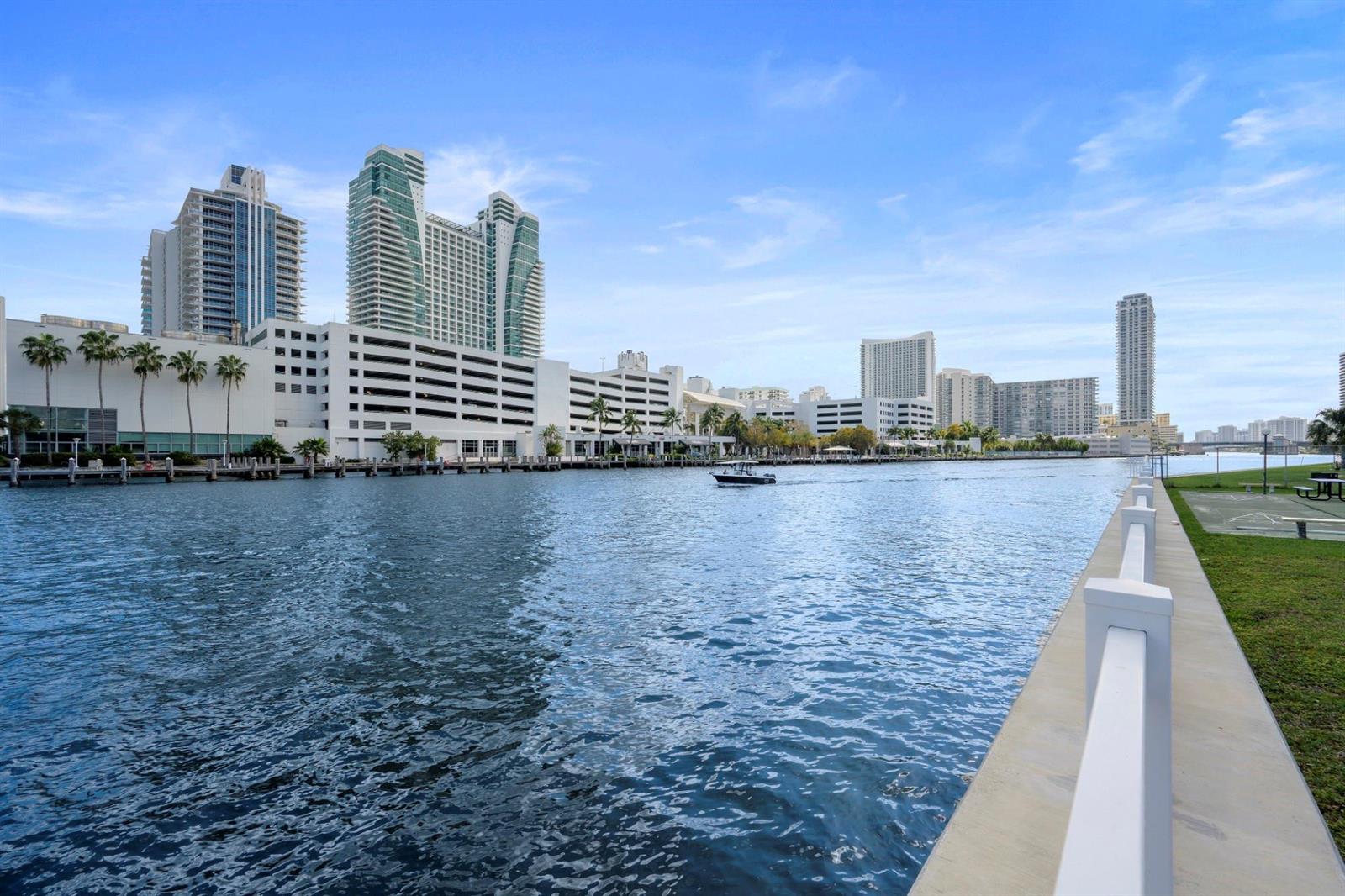 A view of a waterway with a boat, modern high-rise buildings, and a paved walkway — 600 Parkview Drive, Hallandale Beach FL 33009, HALLANDALE BEACH, FL