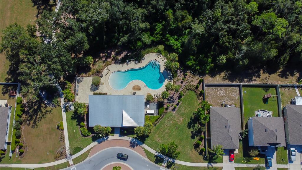 An aerial view shows a community swimming pool, a clubhouse, and surrounding residential homes — 6362 SPIDER LILY WAY, NEW PORT RICHEY, FL
