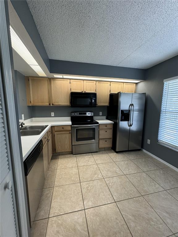 A kitchen with light wood cabinets, stainless steel appliances, dark gray walls, and tile flooring — 13815 TIMBERLAND DRIVE UNIT 103, ORLANDO, FL