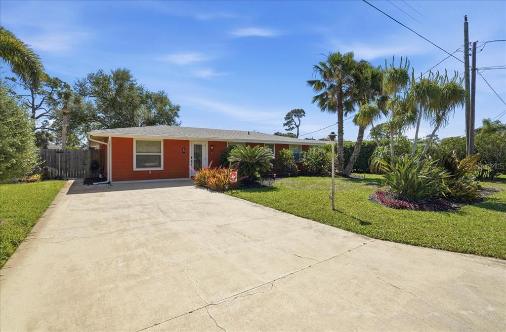 A single-story house with orange siding and a concrete driveway sits on a grassy lot — 1129 RIVIERA STREET, VENICE, FL