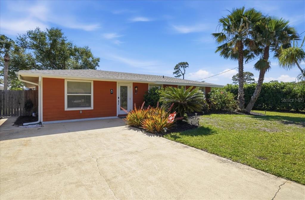 A single-story house with orange siding and a concrete driveway sits under a blue sky — 1129 RIVIERA STREET, VENICE, FL