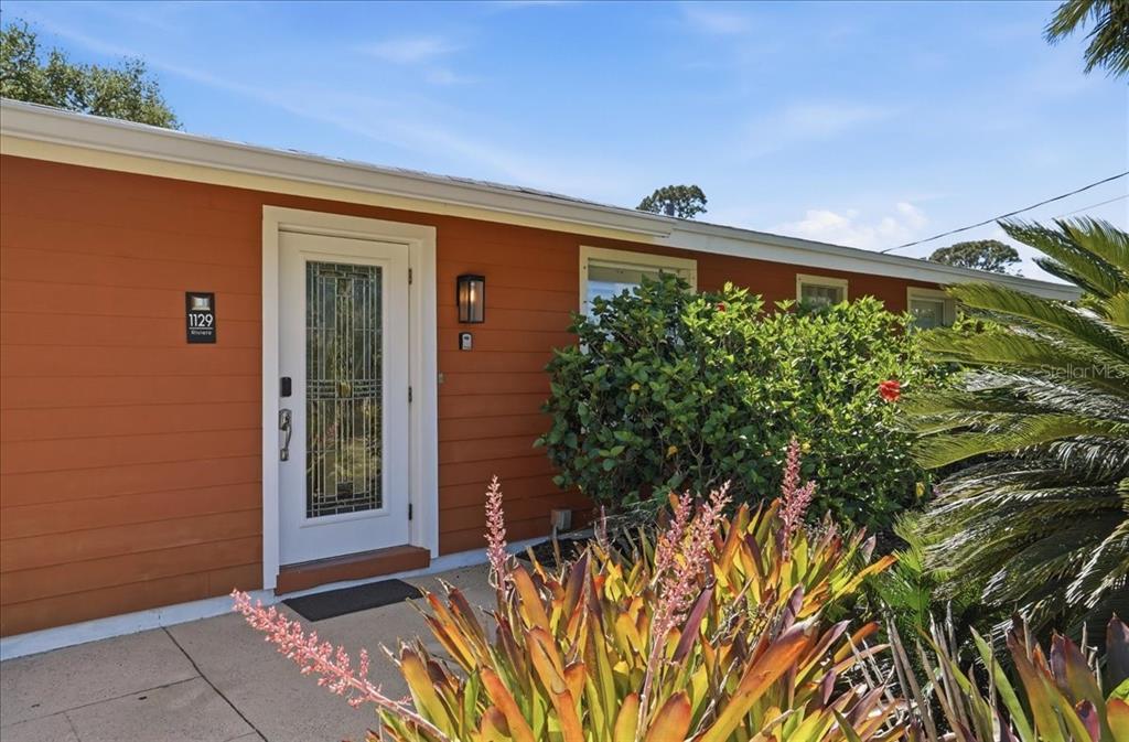 The exterior of a house features orange siding, a white front door, and landscaping — 1129 RIVIERA STREET, VENICE, FL