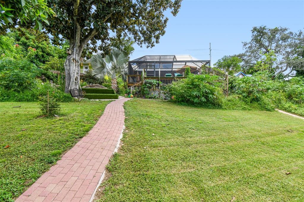 A brick walkway leads across a grassy yard toward a house with a screened porch — 3203 E YUKON STREET, TAMPA, FL