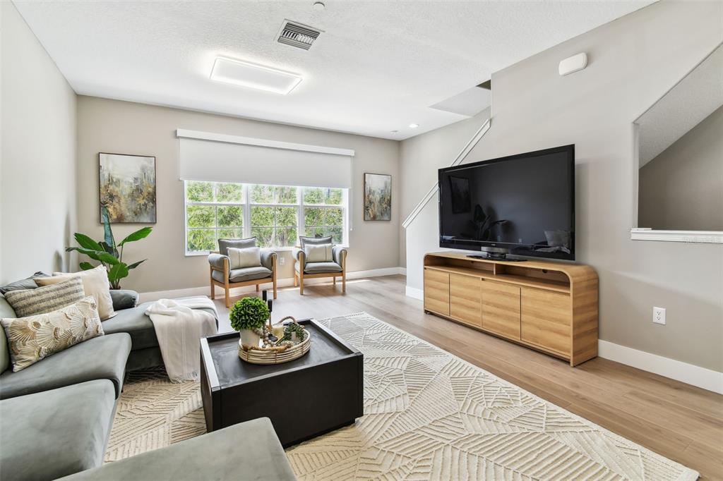 A living room features a grey sectional sofa, two armchairs, and a large television console — 2547 LEXINGTON OAK DRIVE, BRANDON, FL
