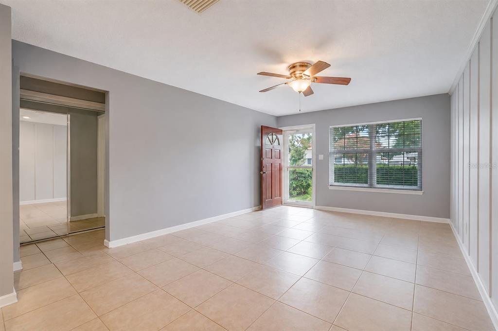 An empty living room with light gray walls, beige tile flooring, and a ceiling fan — 4404 FETROW DRIVE, ORLANDO, FL