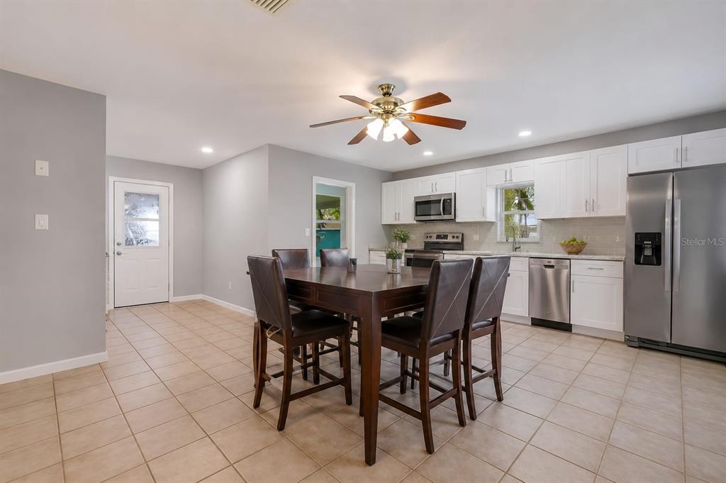 A kitchen and dining area featuring white cabinets, stainless steel appliances, and a dark wood table — 4404 FETROW DRIVE, ORLANDO, FL