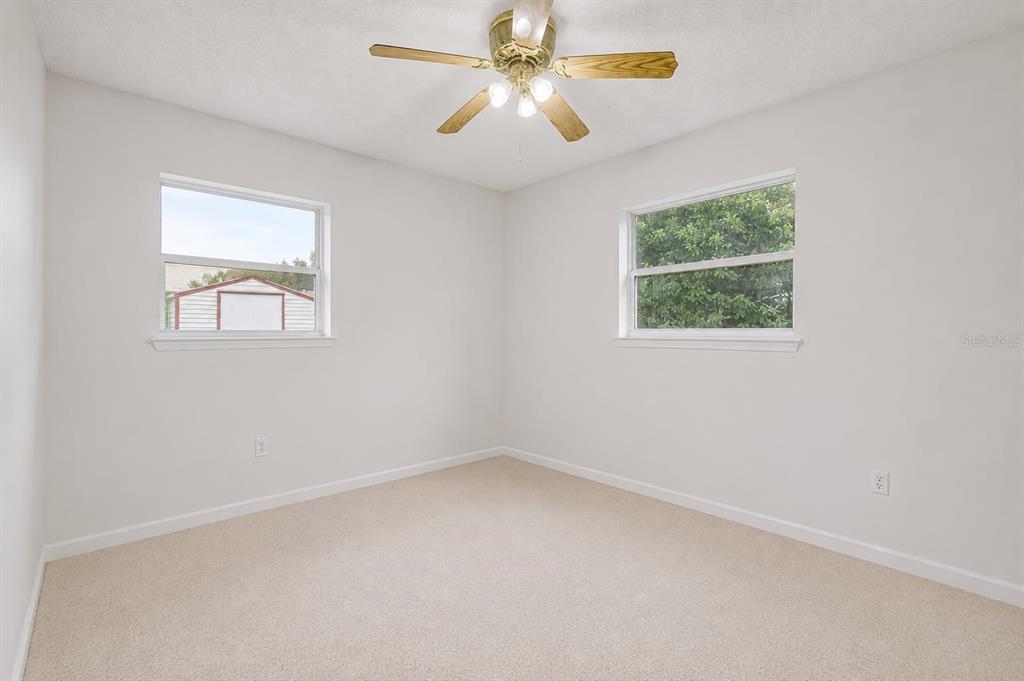 An empty bedroom features beige carpet, white walls, two windows, and a ceiling fan — 4404 FETROW DRIVE, ORLANDO, FL