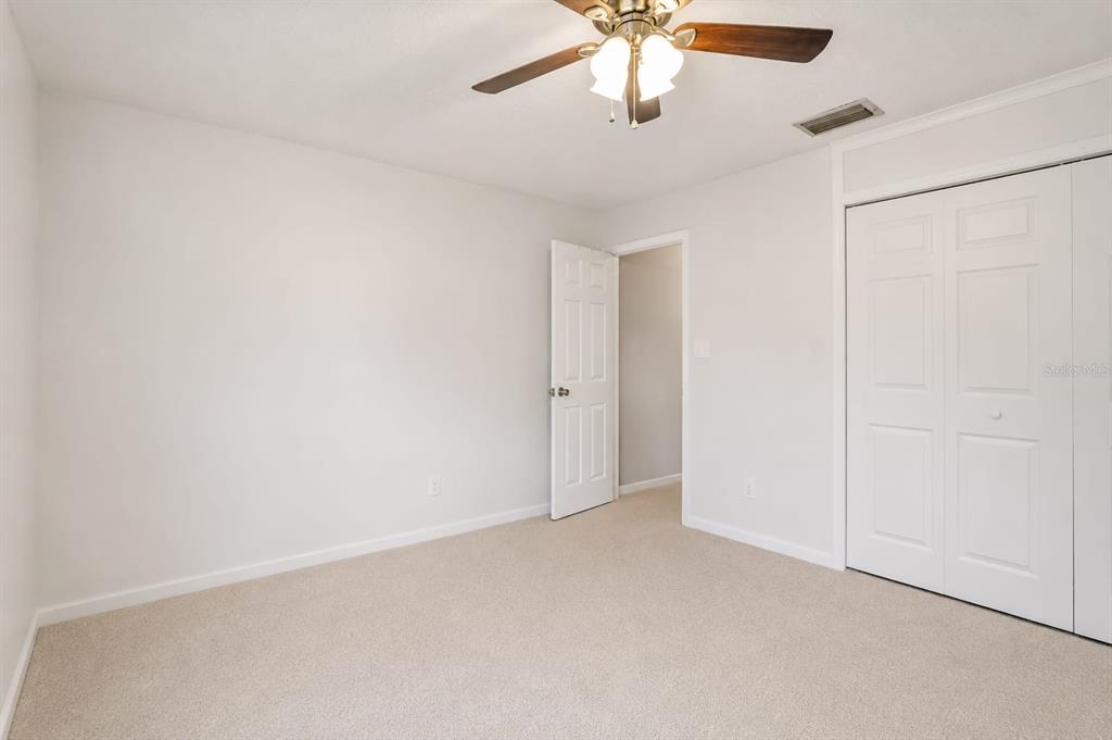 A bedroom with beige carpet, white walls, a ceiling fan, and a white closet door — 4404 FETROW DRIVE, ORLANDO, FL