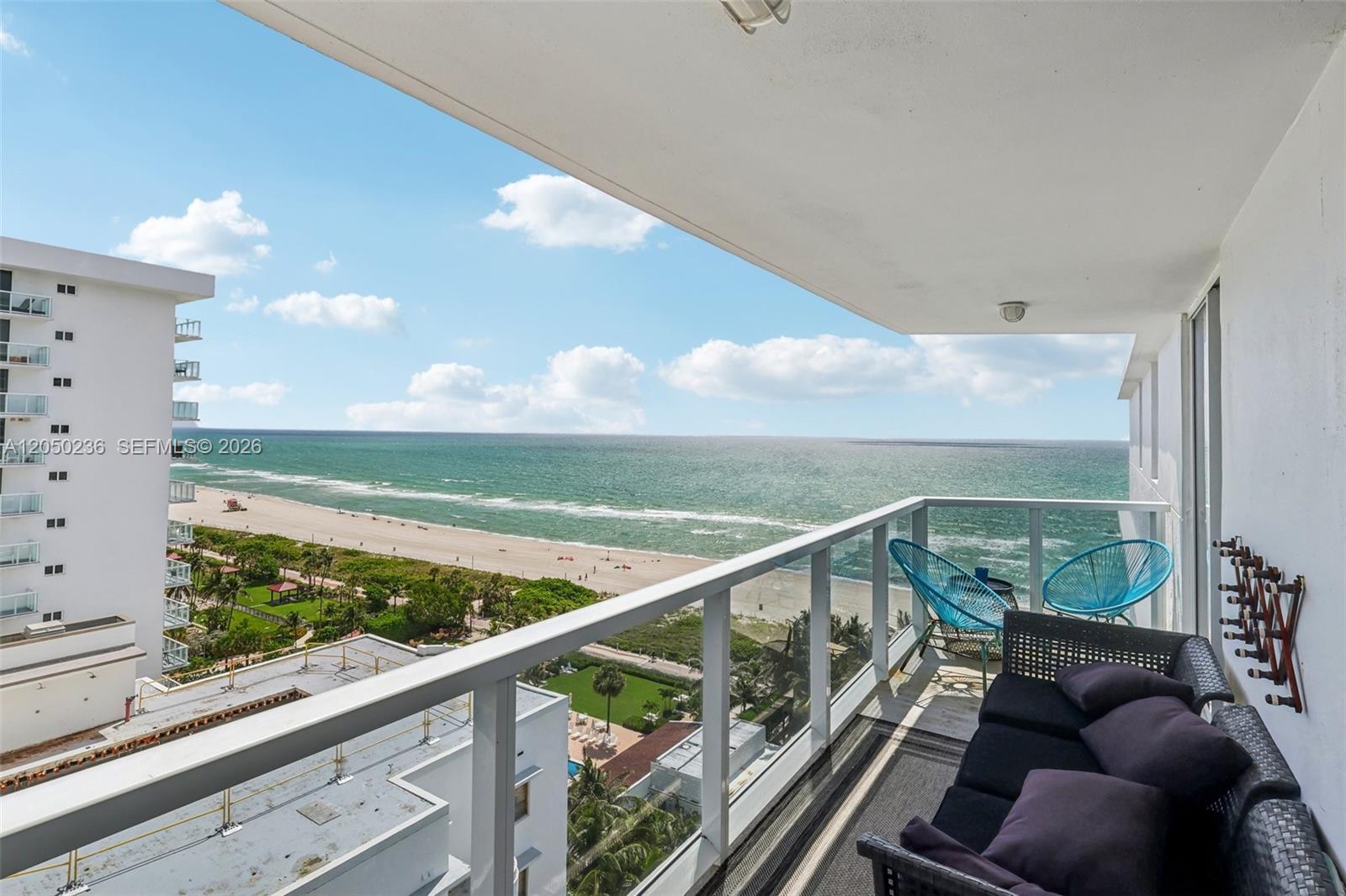A balcony with outdoor furniture overlooks a sandy beach and the ocean — 2401 Collins Ave # 1612, Miami Beach FL 33140, MIAMI BEACH, FL