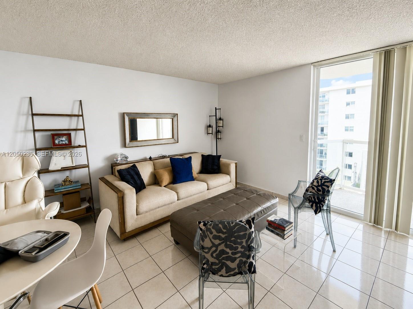 A living room features a beige sofa, a large ottoman, and two transparent chairs — 2401 Collins Ave # 1612, Miami Beach FL 33140, MIAMI BEACH, FL