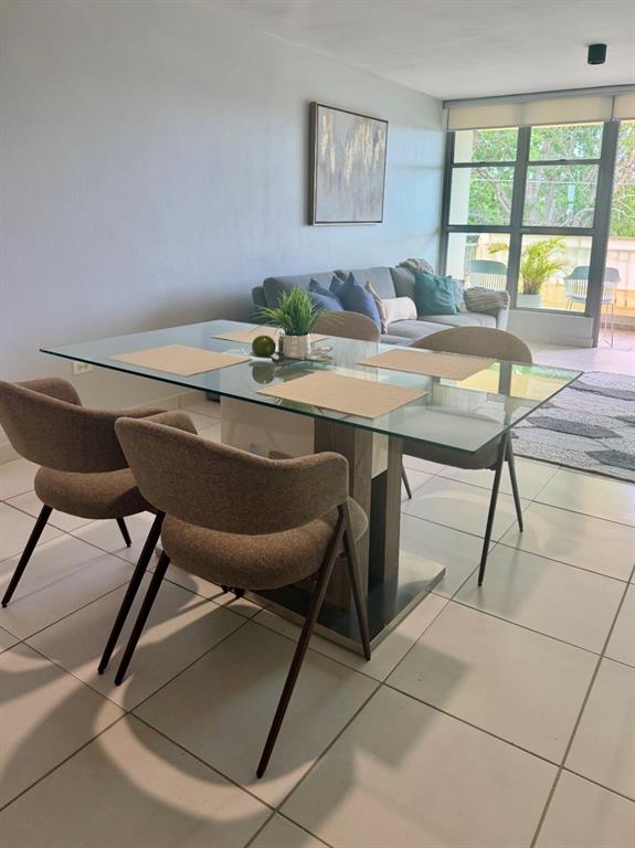 A dining area with a glass-top table and four chairs sits before a living room — Apt 1805 CONDOMINIO LAS PRIMAVERAS UNIT 1805, CAROLINA, PR