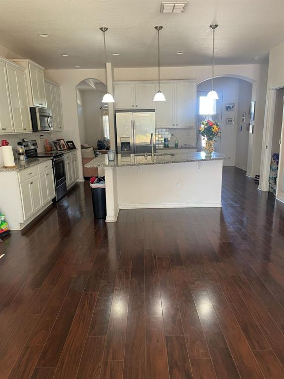 A kitchen features white cabinets, granite countertops, a center island, and dark wood flooring — 12433 BALLENTRAE FOREST DRIVE, RIVERVIEW, FL