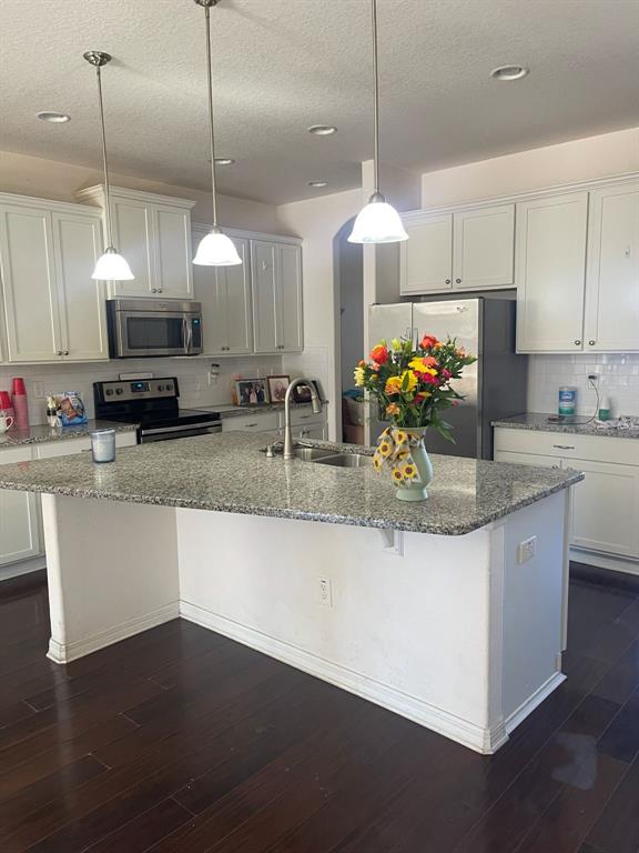 A kitchen features white cabinets, granite countertops, a central island, and dark hardwood flooring — 12433 BALLENTRAE FOREST DRIVE, RIVERVIEW, FL