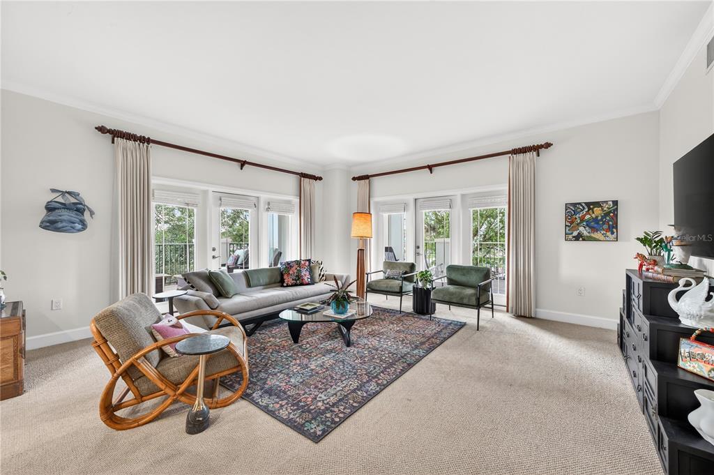 A living room features a gray sofa, patterned area rug, rattan chair, and glass doors — 2305 EDGEWATER DRIVE UNIT 1210, ORLANDO, FL