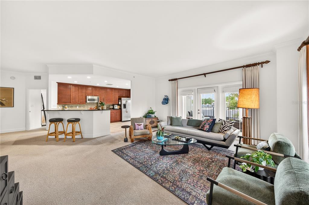 A living room with carpeted floors, a kitchen island with bar stools, and a balcony — 2305 EDGEWATER DRIVE UNIT 1210, ORLANDO, FL