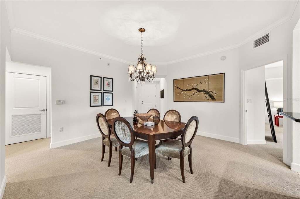 A dining room features a dark wood table, four upholstered chairs, and a decorative chandelier — 2305 EDGEWATER DRIVE UNIT 1210, ORLANDO, FL