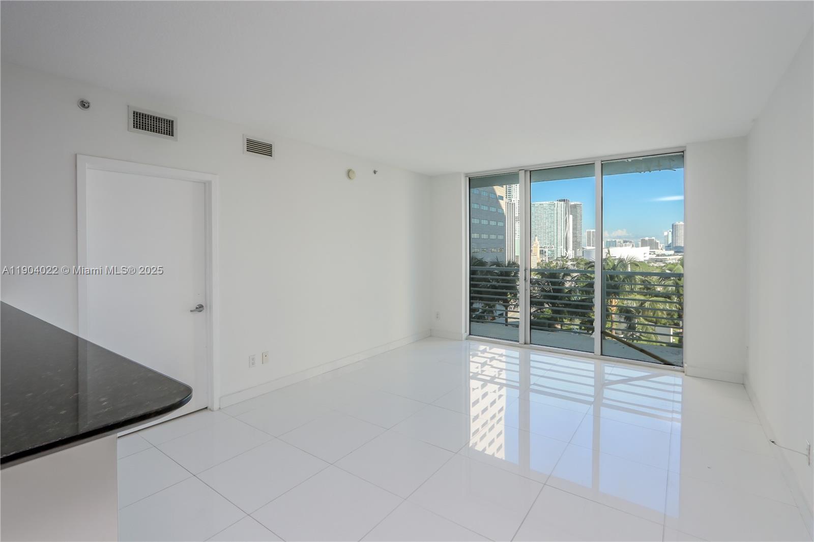 An empty room with white tile floors, white walls, and a balcony overlooking city buildings — 325 S Biscayne Blvd # 1722, Miami FL 33131, MIAMI, FL