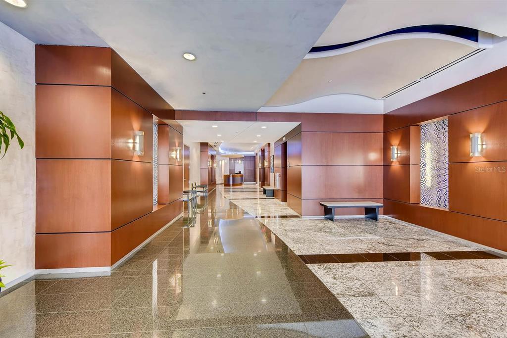 A modern building lobby features wood-paneled walls, polished stone floors, and a curved ceiling design — 111-3 WASHINGTON STREET, ORLANDO, FL