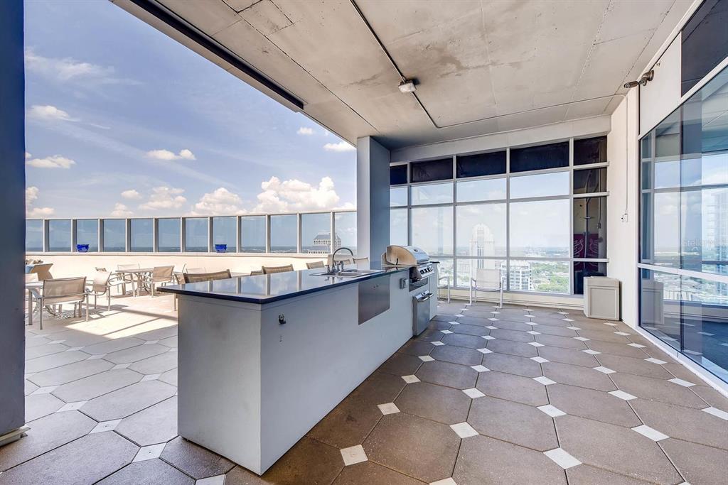 An outdoor balcony features a kitchen island with a grill, sink, and tiled flooring — 111-3 WASHINGTON STREET, ORLANDO, FL