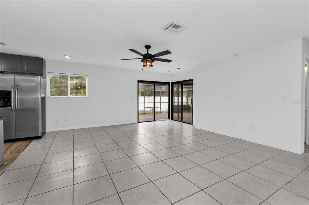 A spacious room with light tile flooring, a ceiling fan, and sliding glass patio doors — 975 BAER AVENUE NW, PORT CHARLOTTE, FL