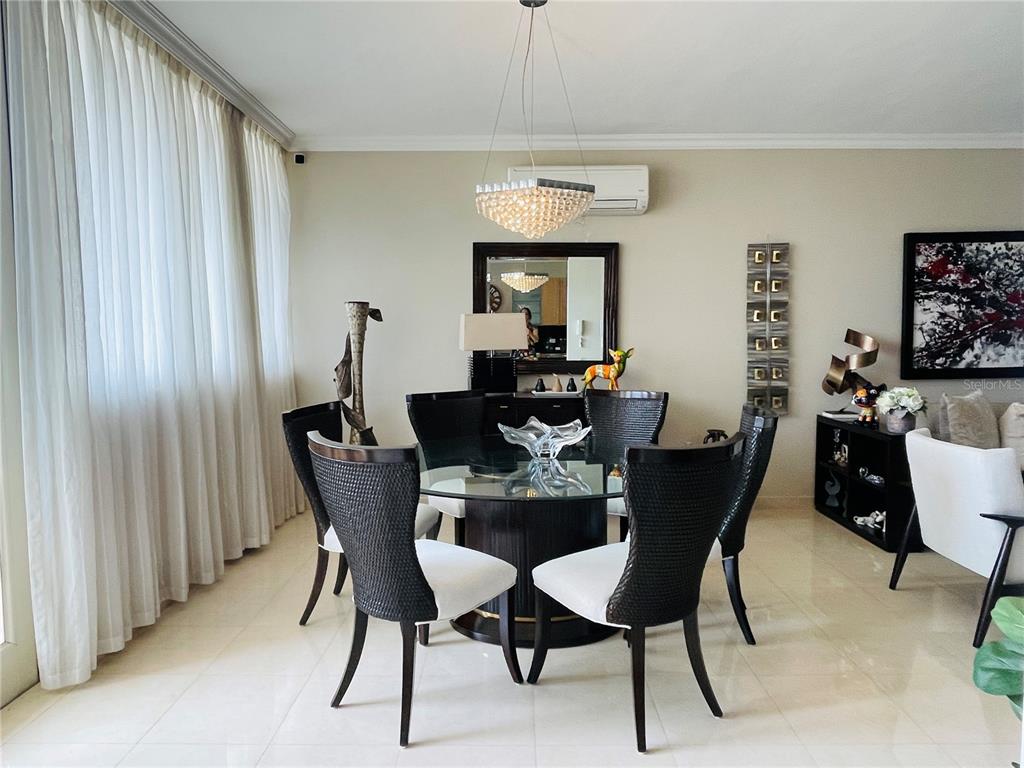 A dining room features a glass-topped table, six dark wicker chairs, and a crystal chandelier — Palma Real Avenue MURANO LUXURY APARTMENTS UNIT 8, GUAYNABO, PR