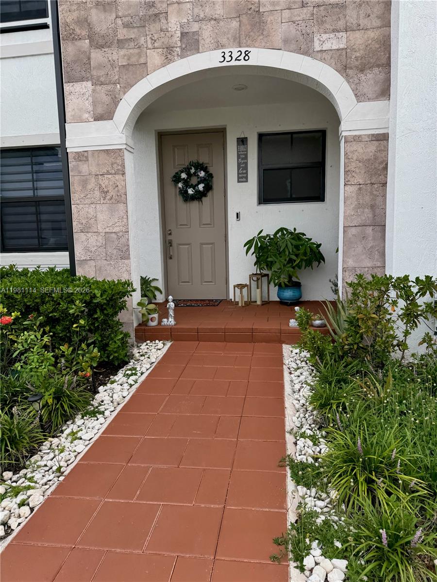 The exterior entrance features a tiled walkway leading to a tan door under an archway — 3328 W 114th Ter # 3328, Hialeah FL 33018, HIALEAH, FL