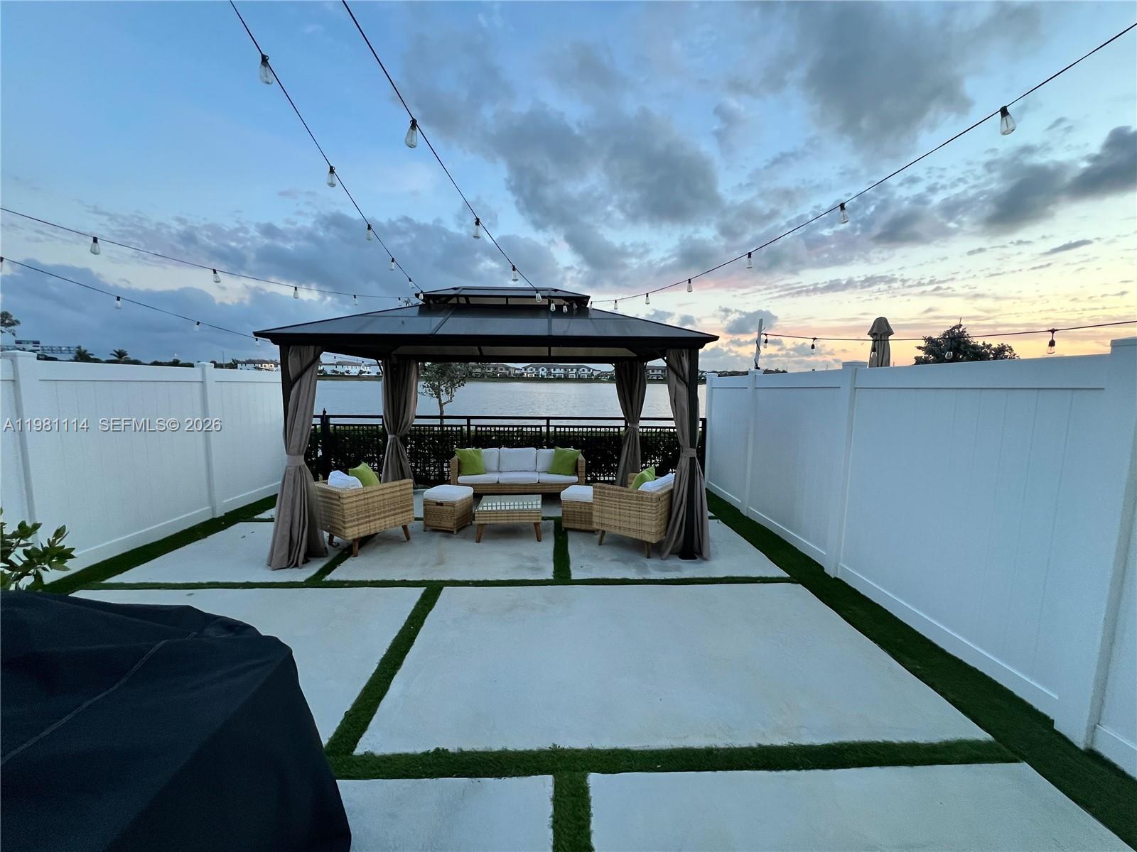 A backyard patio features a gazebo with outdoor furniture, concrete pavers, and a white fence — 3328 W 114th Ter # 3328, Hialeah FL 33018, HIALEAH, FL