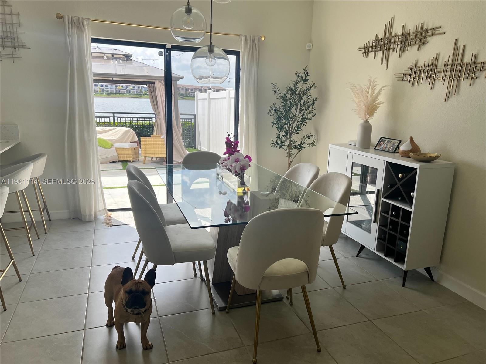 A dining room with a glass table, white chairs, and a view of a lake — 3328 W 114th Ter # 3328, Hialeah FL 33018, HIALEAH, FL