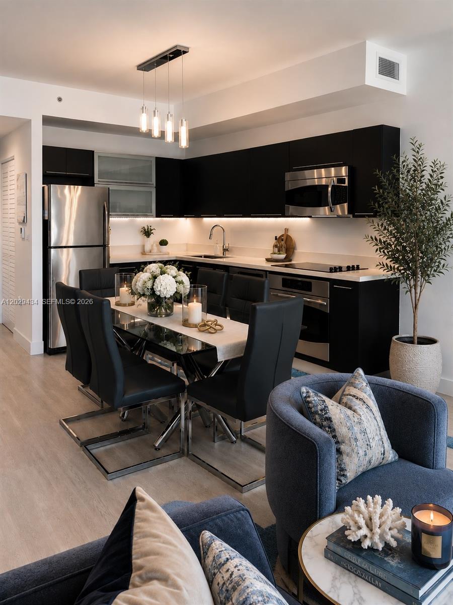 A modern kitchen features black cabinetry, stainless steel appliances, and an adjacent dining area — 90 SW 3rd St # 1703, Miami FL 33130, MIAMI, FL