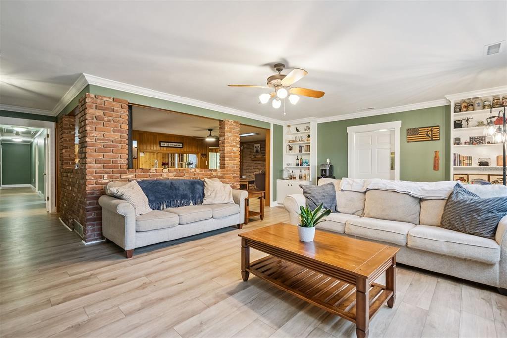 A living room features light wood floors, two sofas, and a brick partition wall — 1000 BOYLSTON STREET, LEESBURG, FL