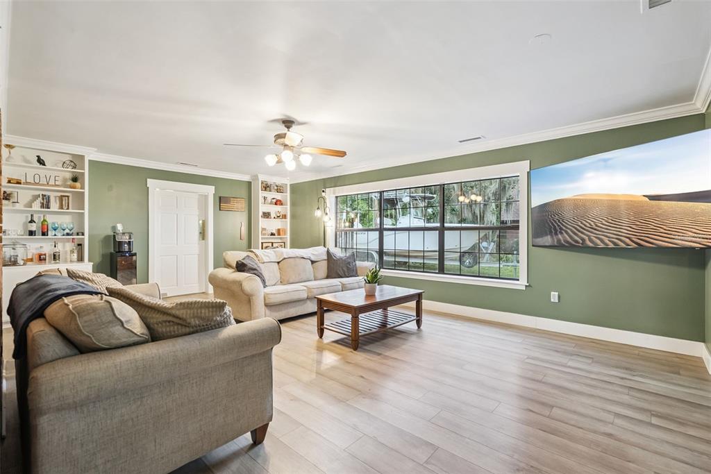 A living room features green walls, light wood flooring, two sofas, and a large television — 1000 BOYLSTON STREET, LEESBURG, FL