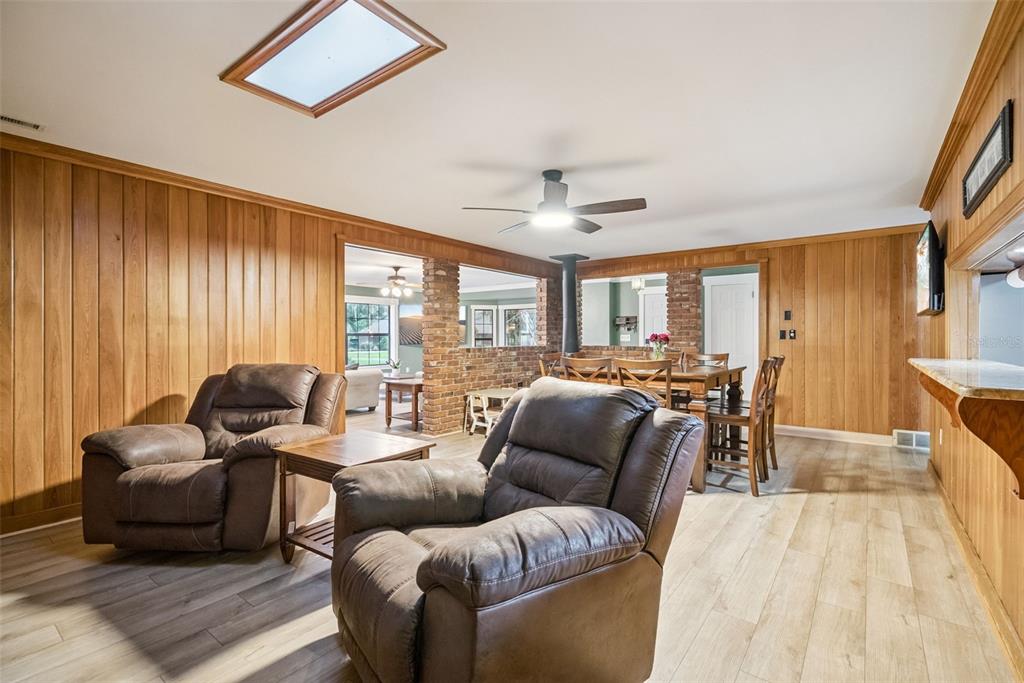 A living and dining area features wood-paneled walls, brick accents, and light-colored wood flooring — 1000 BOYLSTON STREET, LEESBURG, FL