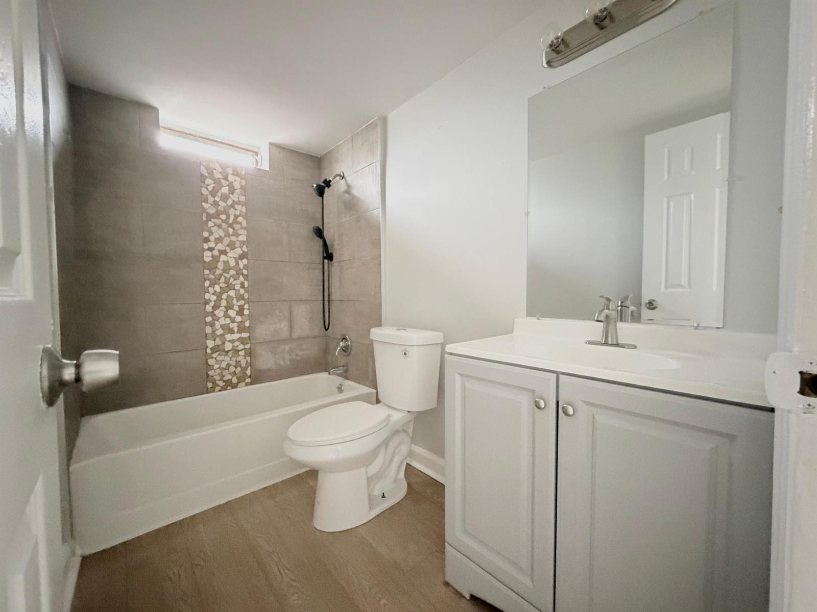 A bathroom featuring a tub-shower combo with tiled accents, a toilet, and a vanity cabinet — 1501 Crescent Circle # E45, Lake Park FL 33403, LAKE PARK, FL