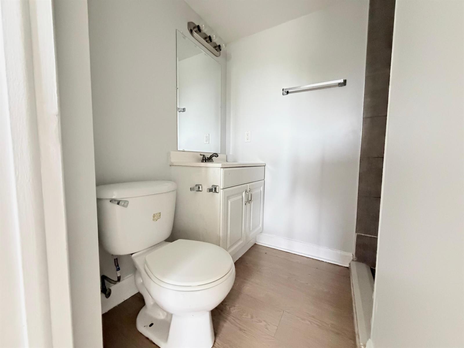 A bathroom with a white toilet, a vanity with a mirror, and light wood flooring — 1501 Crescent Circle # E45, Lake Park FL 33403, LAKE PARK, FL