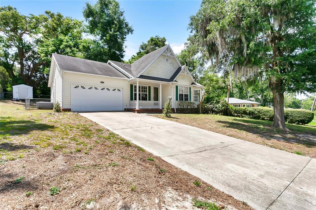 A light-colored single-story house with a two-car garage and a concrete driveway — 1311 HILLTOP DRIVE, MOUNT DORA, FL