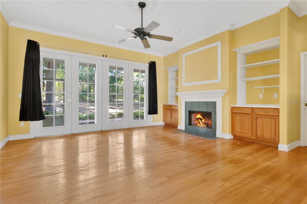 A living room with yellow walls, hardwood floors, a fireplace, and glass patio doors — 1311 HILLTOP DRIVE, MOUNT DORA, FL
