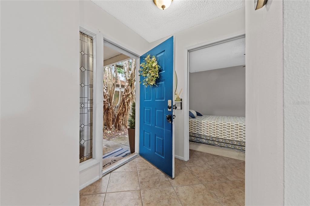 An entryway with tile flooring, a blue front door, and a view into a bedroom — 335 KIRKCALDY DRIVE, WINTER SPRINGS, FL