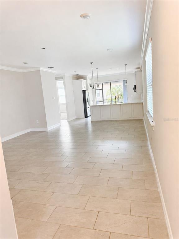 An open-concept kitchen and living area features light-colored tile flooring and white cabinetry — 120 MOSCATA WAY, NOKOMIS, FL