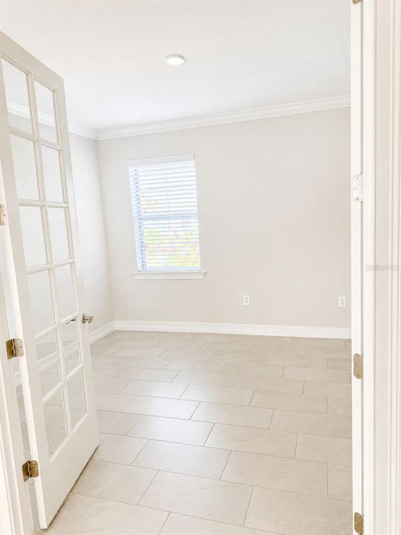 An empty room with light-colored tile flooring, white walls, and French doors — 120 MOSCATA WAY, NOKOMIS, FL
